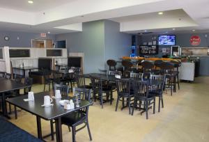 a restaurant with tables and chairs and a bar at All Stay Suites in Westlock