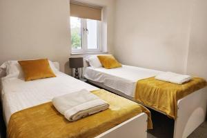 a bedroom with two beds with yellow sheets and a window at Horizon House, Luxury 2-Bedroom Flat 3 in Oxford