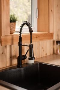 a kitchen sink with a black faucet next to a window at Chalet La Renarde in Nouvelle