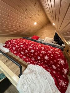 a bed in a wooden room with a red blanket at Challet44 in Jeseník