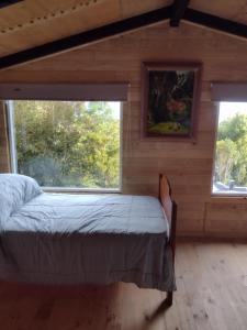 a bedroom with a bed in a room with two windows at Casa Aoni in Puerto Montt
