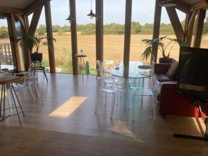 a glass table and chairs in a room with a field at Country Escape at the Granary in Colchester