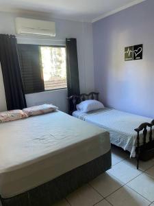 a bedroom with two beds and a window at Apto 2 quadras da Praia do Tombo in Guarujá