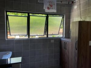 a bathroom with two windows and a tiled wall at Apto 2 quadras da Praia do Tombo in Guarujá