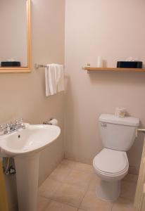 a bathroom with a white toilet and a sink at All Stay Suites in Westlock