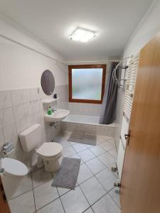 a bathroom with a toilet and a sink and a tub at Ferienwohnung in Wrist