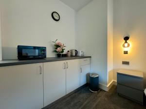 a kitchen with white cabinets and a clock on the wall at Seafarers Stays in Southampton