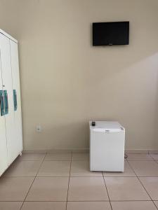 a white refrigerator in a room with a tv on a wall at Recanto Resplendor in Olímpia