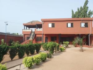 una casa roja con una fila de plantas delante de ella en Villa 28 en Lomé