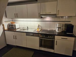 Una cocina con gabinetes blancos, un fregadero y un microondas. en Waldhof Golf-Fewo, en Korswandt 6 fotos más