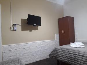 um quarto com uma cama e uma televisão na parede em Hospedaje Del Centro em Paso de los Libres