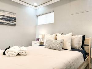 um quarto com uma cama grande com lençóis brancos e almofadas em Colorado Spa Retreat / HOT TUB/SAUNA / downtown em Colorado Springs