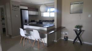 a kitchen with a counter and white chairs in it at 2 bedroom morden apartment in Fairview