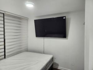 1 dormitorio con TV de pantalla plana en la pared en Vivaceta Metro Hospitales, en Santiago