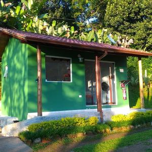 ein kleines grünes Haus mit einem großen Fenster in der Unterkunft Chalés Vale dos Pássaros in Paraty