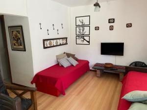 sala de estar con cama roja y TV de pantalla plana en ARENAS 4 en Villa Gesell