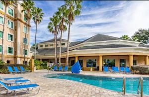 una piscina resort con sillas azules y palmeras en Resort Condo Top floor pool view -Disney Parks Free Shuttle, en Orlando