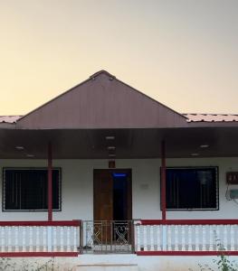 a white building with a black roof and a door at Janhavi Villa in Dapoli