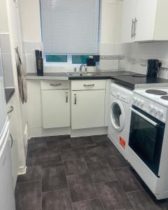 a kitchen with white cabinets and a washer and dryer at Sleek Cosy Flat Camden in London