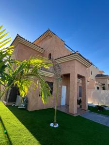 a house with a palm tree in front of it at Villa Saona Golf in San Miguel de Abona