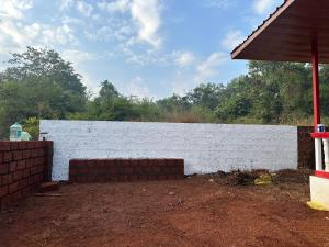 a white brick wall in a yard with trees at Janhavi Villa in Dapoli