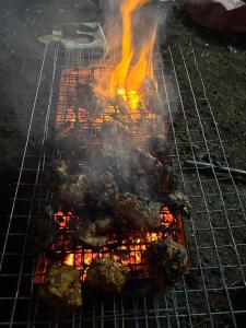 a grill with meat and flames on it at Janhavi Villa in Dapoli