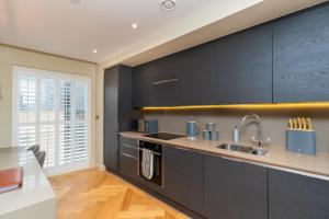 a kitchen with black cabinets and a sink at Entire Apartment - City Centre - Free Parking in York