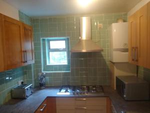 a green tiled kitchen with a stove and a window at London Central Acton Aparthotel in London