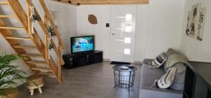 uma sala de estar com um sofá e uma televisão em Le cocon des bois em Martigues