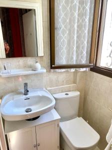 ein Badezimmer mit einem Waschbecken, einem WC und einem Spiegel in der Unterkunft RETIRO V - Los Quesitos in Denia