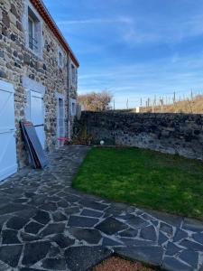 a stone patio with a stone wall next to a building at Gîte mitoyen gorges de la Monne - Olloix in Olloix