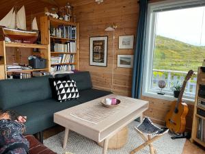 a living room with a couch and a table and a guitar at Aurora exotic cabin in Vannareid