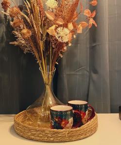 Un jarrón con flores y dos tazas en una mesa. en Blush Jungle en Dublín