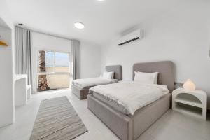 a white bedroom with two beds and a window at Jumeirah Three Bedroom House in Dubai