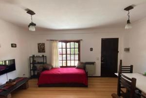 1 dormitorio con cama roja y ventana en ARENAS 4 en Villa Gesell
