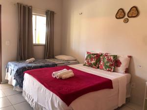 um quarto com 2 camas e um cobertor vermelho em Pousada Chácara do Coqueiro em Barreirinhas