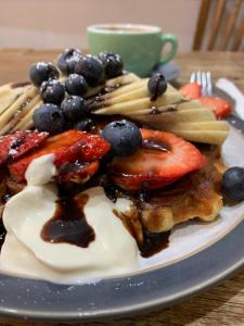 a plate of pancakes with fruit and a cup of coffee at London Comfort Stay in London