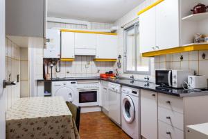 cocina con armarios blancos, lavadora y secadora en VUT Casa Trujillano, en Ávila