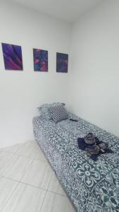 a bed in a room with paintings on the wall at Vaccani Apart in Macaé