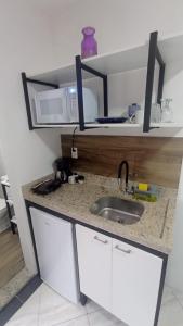 a kitchen counter with a sink and a microwave at Vaccani Apart in Macaé
