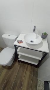 a white bathroom with a toilet and a sink at Vaccani Apart in Macaé