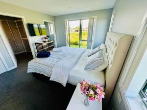 a bedroom with a bed and flowers on a table at Maple Retreat by Blue Spring in Putaruru