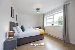 um quarto com uma cama e uma janela em Bright & Spacious 3 Bedroom Home With Fast Wifi! em Wythenshawe