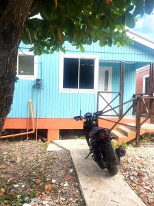 ein Motorrad, das vor einem blauen Haus parkt in der Unterkunft Casa Nativa DUDA´S in Franshua