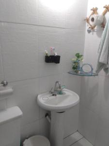Baño blanco con lavabo y aseo en Quarto Casal privativo em apartamento, en Salvador