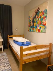 a bedroom with a wooden bed with a painting on the wall at Fristad Hostel Vitsand in Gunsjögården