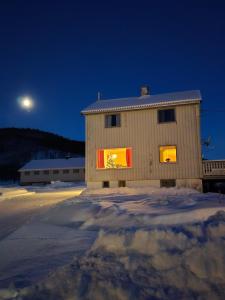 特羅姆瑟的住宿－Tønsvik enebolig，一座晚上窗户上灯的建筑