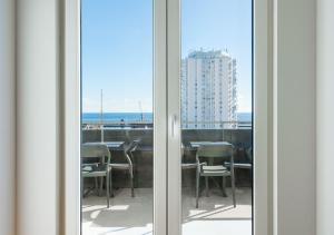 uma porta de vidro deslizante com vista para uma mesa e cadeiras em Sky PDL em Ponta Delgada