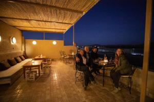 a group of people sitting at tables on a balcony at Dar Duna in Adrouine