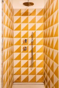 a bathroom with a shower with yellow and white tiles at Sartoria Cavour - Modern Sicilian Elegance in a Former Tailor Shop in Palermo